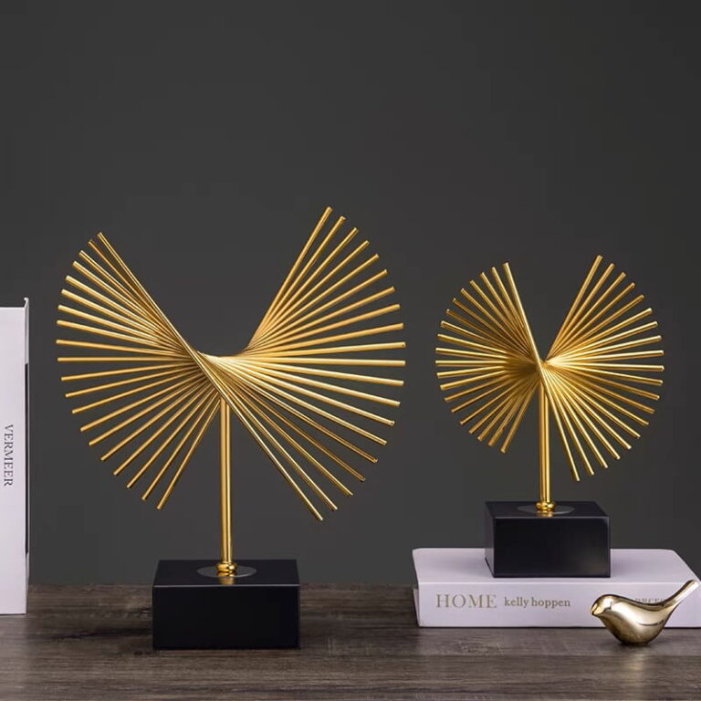 Modern gold decorative sculptures on a table with books, ideal for luxury home decor.