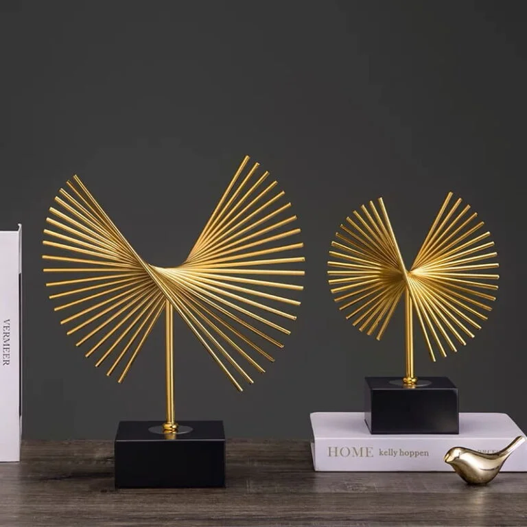 Modern gold decorative sculptures on a table with books, ideal for luxury home decor.