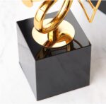 Gold decorative sculpture on black base, modern home decor accessory.