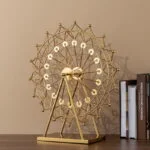Gold Ferris wheel sculpture on a table with books, modern home decor accessory.