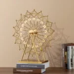 Gold decorative Ferris wheel sculpture on a table with books, modern home decor.