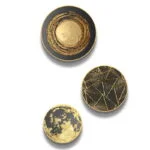 Set of three round gold and black modern wall art pieces with abstract designs.