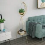 Modern gold planter stand with crescent moon design in a stylish living room.