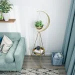 Modern gold planter stand with hanging plant in a stylish living room corner.