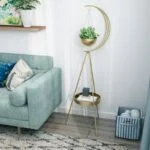 Modern gold planter stand with decorative plant in a stylish living room corner.