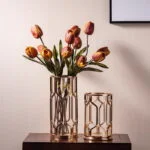 Elegant gold decorative vases with tulips on a wooden table, modern home decor.