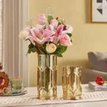 Elegant gold decorative vases with pink and white flowers on a modern table.