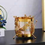 Gold decorative candle holder with leaf design on a black shelf.