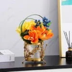 Elegant gold decorative vase with vibrant flowers on a modern shelf.