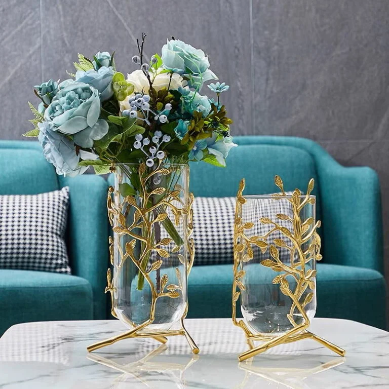 Elegant glass vases with gold leaf design on a marble table in a modern living room.