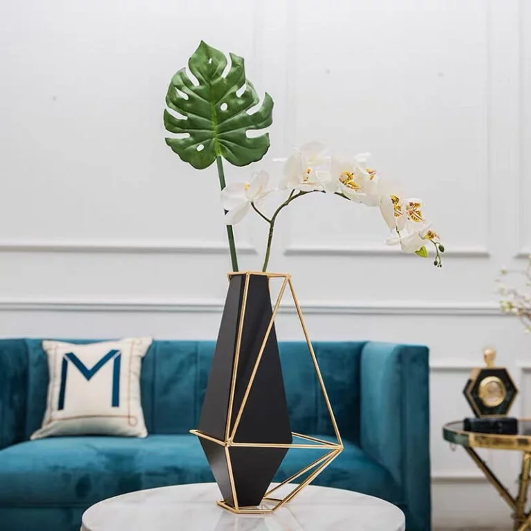 Modern geometric vase with flowers on a marble table in a luxury living room.
