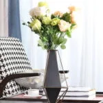 Modern geometric vase with flowers on a table in a stylish living room.