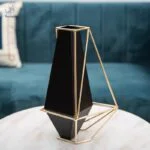 Modern black vase with gold geometric frame on a marble table, luxury home decor accessory.