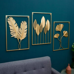 Gold metal wall art with leaf designs on a teal wall above a gray sofa.