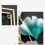 Modern metal wall art with gold frame and teal leaf design.