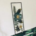 Modern floral wall art with gold and green accents in a black frame.