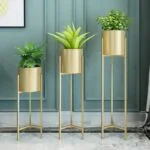 Modern gold metal planters with green plants in a stylish interior setting.