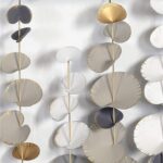 Modern metal wall art with circular gold and silver accents.
