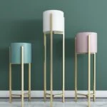 Modern decorative planters with gold stands in a stylish interior setting.