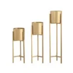 Set of three gold metal planters with stands for modern home decor.