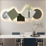Modern illuminated wall art with geometric shapes and vase design in a contemporary dining room.