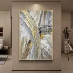 Modern abstract wall art with gold and gray tones in a luxury living room setting.