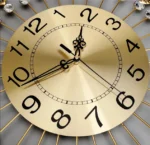 Luxury gold wall clock with black numerals and decorative accents.