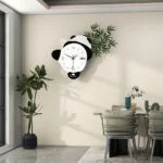 Modern panda-shaped wall clock in a stylish dining room with plants and elegant decor.