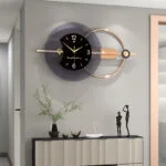 Modern luxury wall clock with gold accents and decorative figurines on a console table.