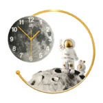 Modern wall clock with astronaut and moon design, gold accents, luxury home decor.