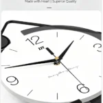 Modern black and white wall clock with sleek design and Arabic numerals.