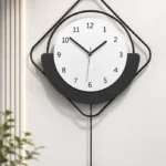 Modern black and white wall clock with geometric design and pendulum.