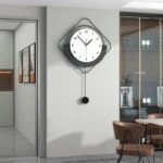 Modern luxury wall clock with pendulum in a stylish living room setting.