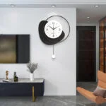 Modern luxury wall clock in a stylish living room with decorative vase and sculpture.