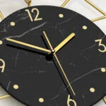 Modern luxury wall clock with black marble face and gold accents.