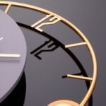 Modern luxury wall clock with gold accents on a reflective surface.