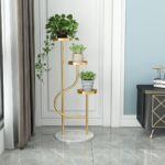 Elegant gold indoor planter with three levels, featuring lush green plants, in a modern living room setting.