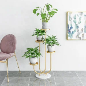 Modern gold plant stand with green plants and framed cactus wall art in a stylish room.
