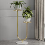 Modern gold metal planter with two potted plants on a marble base, ideal for luxury home decor.