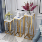 Modern gold and marble plant stands with decorative vases in a luxury living room.