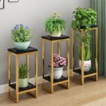 Modern gold plant stands with decorative indoor planters and green plants.