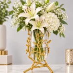 Elegant gold branch vase with white flowers on a marble surface, modern home decor.