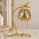 Gold bird branch mantel clock on marble surface, modern luxury home decor.