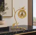 Golden branch clock with bird design on a marble table, modern home decor.