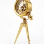 Vintage golden steampunk tripod clock with exposed gears and Roman numerals.