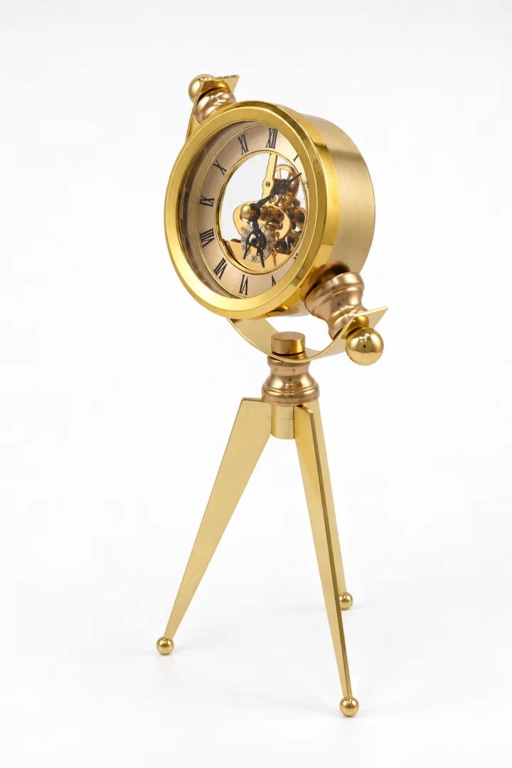 Vintage golden steampunk tripod clock with exposed gears and Roman numerals.